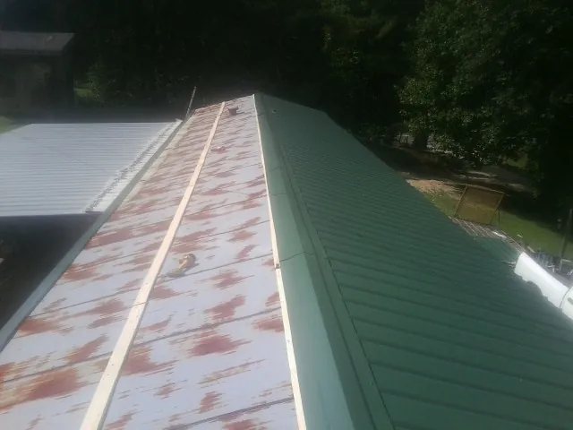 Old rusted panels beside newly installed green metal roofing — Wind Damage Roof Repair by Roofing Brothers in York