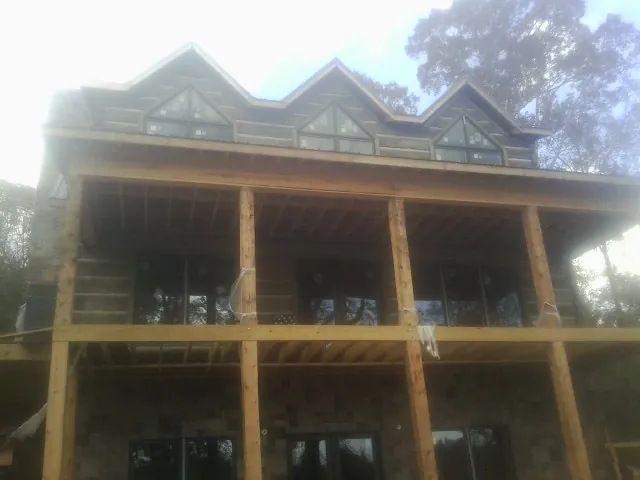 Dormers and porch framing on a large log home under construction — Roof Coating work by our crew in York